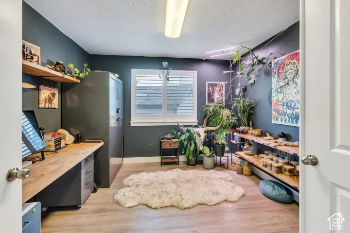 Light wood-finish flooring, built-in wooden shelving, and a window with white louvered shutters