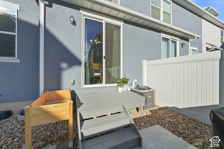 Exterior featuring a sliding glass door, composite deck with steps, gravel landscaping, and a white vinyl privacy fence