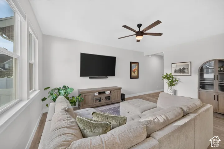 Recessed lighting, wood-finish flooring, ceiling fan with light fixture, built-in display cabinet with arched top, and large windows