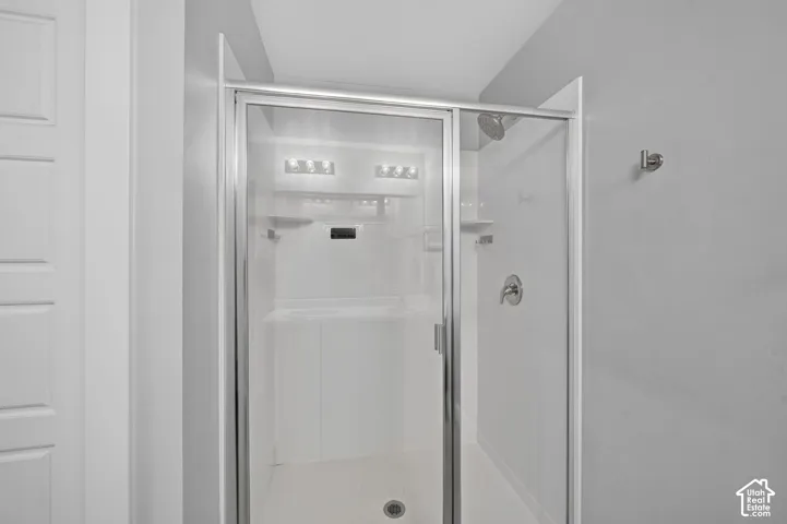 Shower enclosure with clear glass panels, chrome hardware, built-in shelving, and a wall-mounted showerhead
