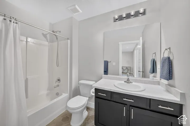 White tub-shower combination, single vanity with a white countertop, dark-finish cabinetry, and a vanity mirror with a four-light fixture