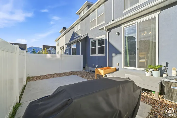 Private backyard with a concrete patio, white privacy fencing, and a raised wooden planter