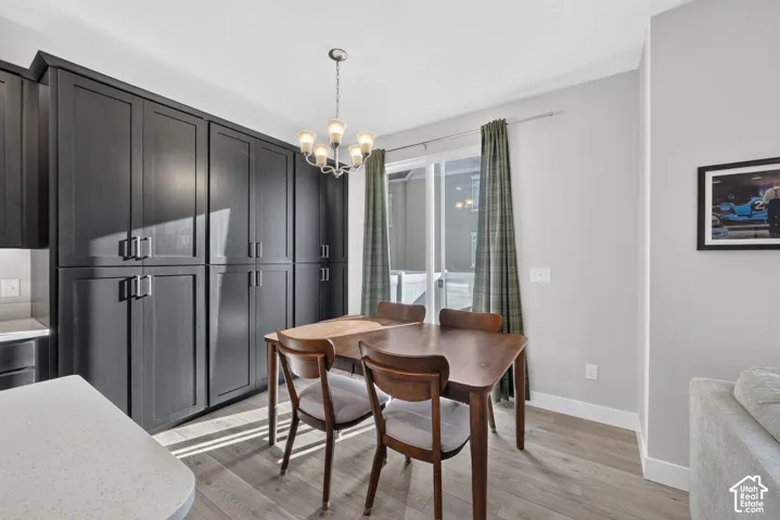 Full-height cabinetry, sliding glass door, overhead chandelier, light wood-finish flooring, and light-toned walls