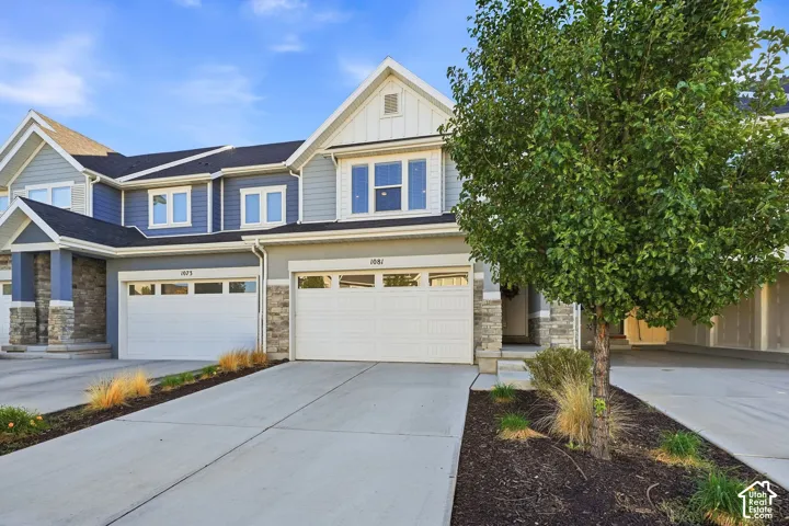 Multi-story exterior with a mix of light blue and gray siding, stone accent columns, and multiple white-framed windows