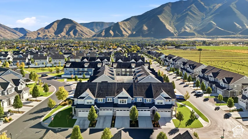 Residential community with mountain backdrop, featuring multiple single-family residences and townhomes, landscaped common areas, and paved roadways