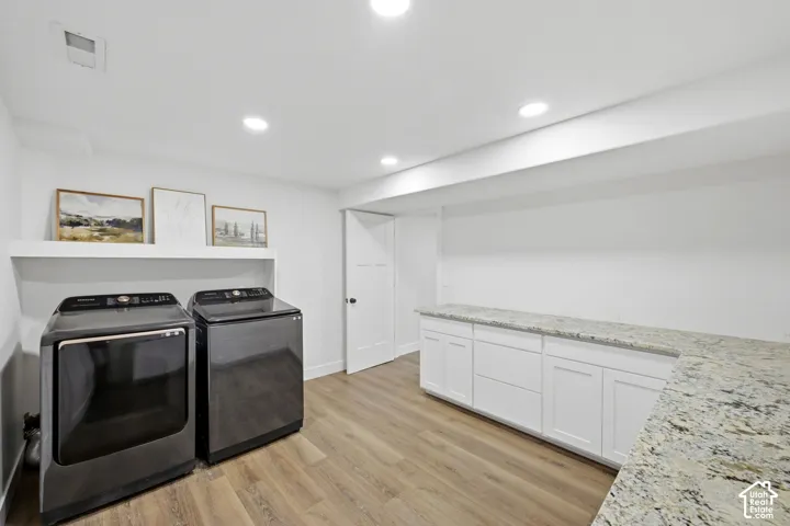 Recessed lighting, wood-finish flooring, white cabinetry, expansive countertop, and a floating shelf