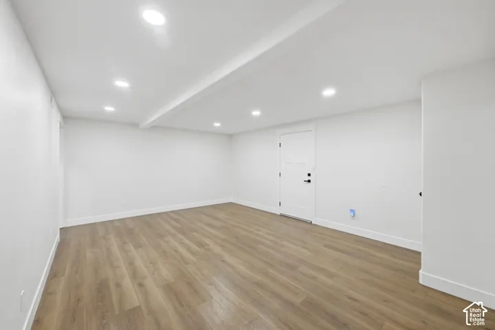 Recessed lighting, wood-finish flooring, white trim, and a paneled door