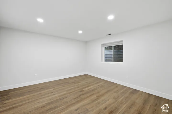 Recessed lighting, wood-finish flooring, white walls, white trim, and a horizontal sliding window