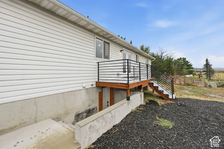 White horizontal siding exterior with a wood deck, black metal railings, and concrete exterior stairs