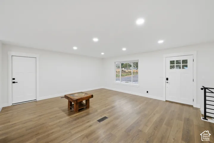 Recessed lighting, wood-finish flooring, white trim, white doors, and a window with exterior visibility