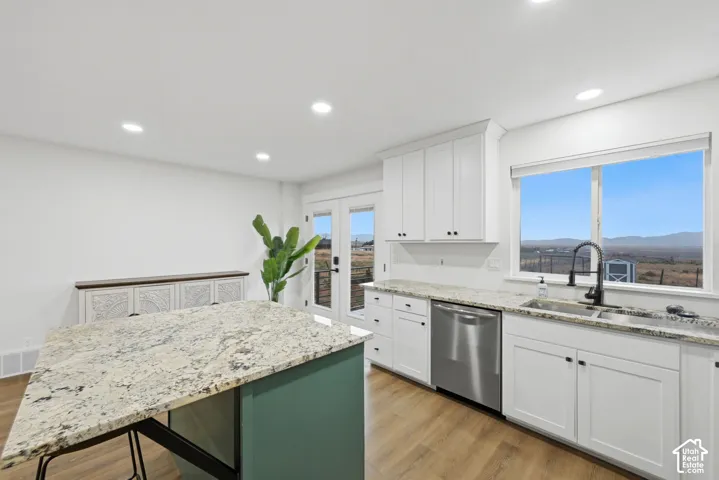 Kitchen featuring white cabinetry, stone-finish countertops, stainless steel dishwasher, and wood-finish flooring