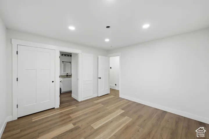 Recessed lighting, wood-finish flooring, white trim, and white interior doors