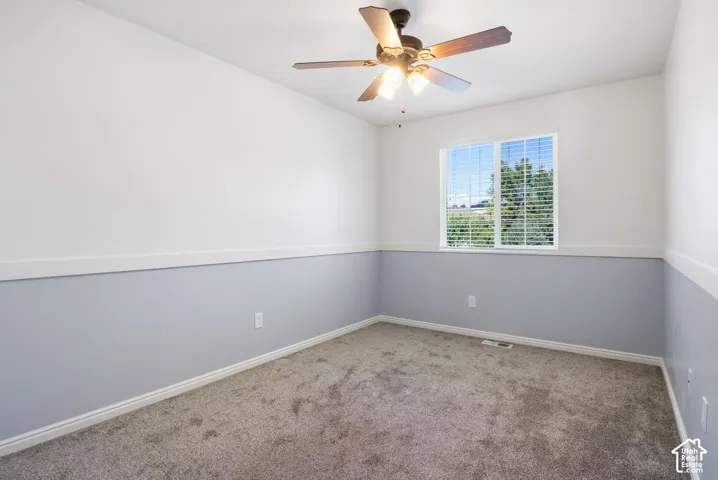 Carpeted room with a ceiling fan, window with blinds, and two-tone wall treatment