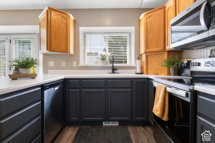 Kitchen featuring wood-finish flooring, white countertops, dark lower cabinetry, and light wood upper cabinetry