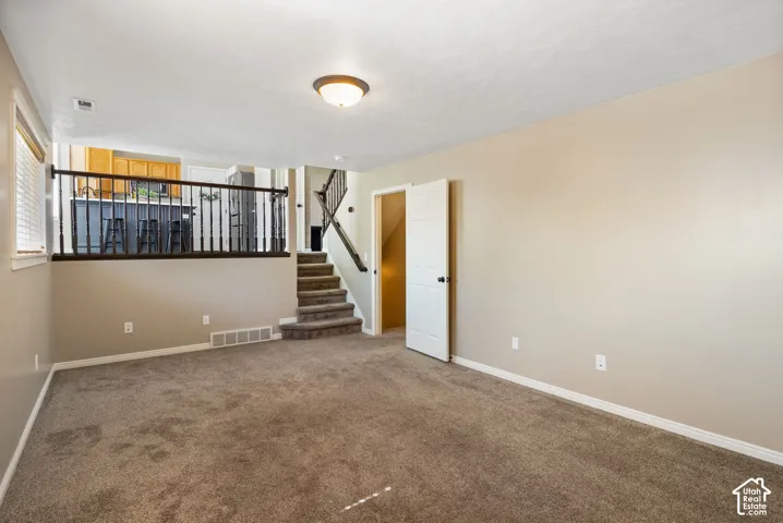 Carpeted lower level with neutral wall tones and a built-in staircase