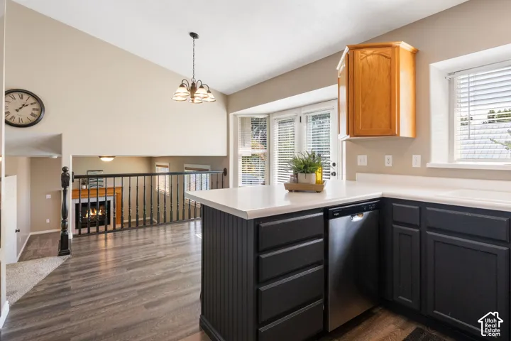 Kitchen island with beadboard paneling, light countertops, wood-finish flooring, and a vaulted ceiling