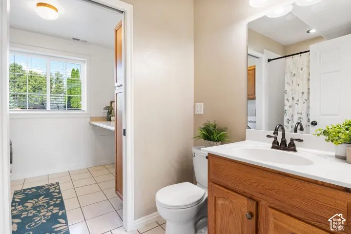 Bathroom featuring a wood-finish vanity with an integrated sink, a large wall-mounted mirror, and tile flooring