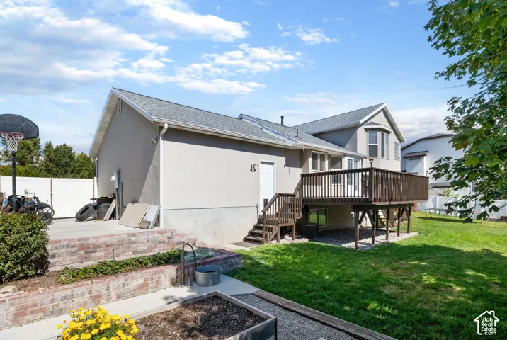 Expansive backyard with a manicured lawn, multi-level wood deck, and a raised planter bed