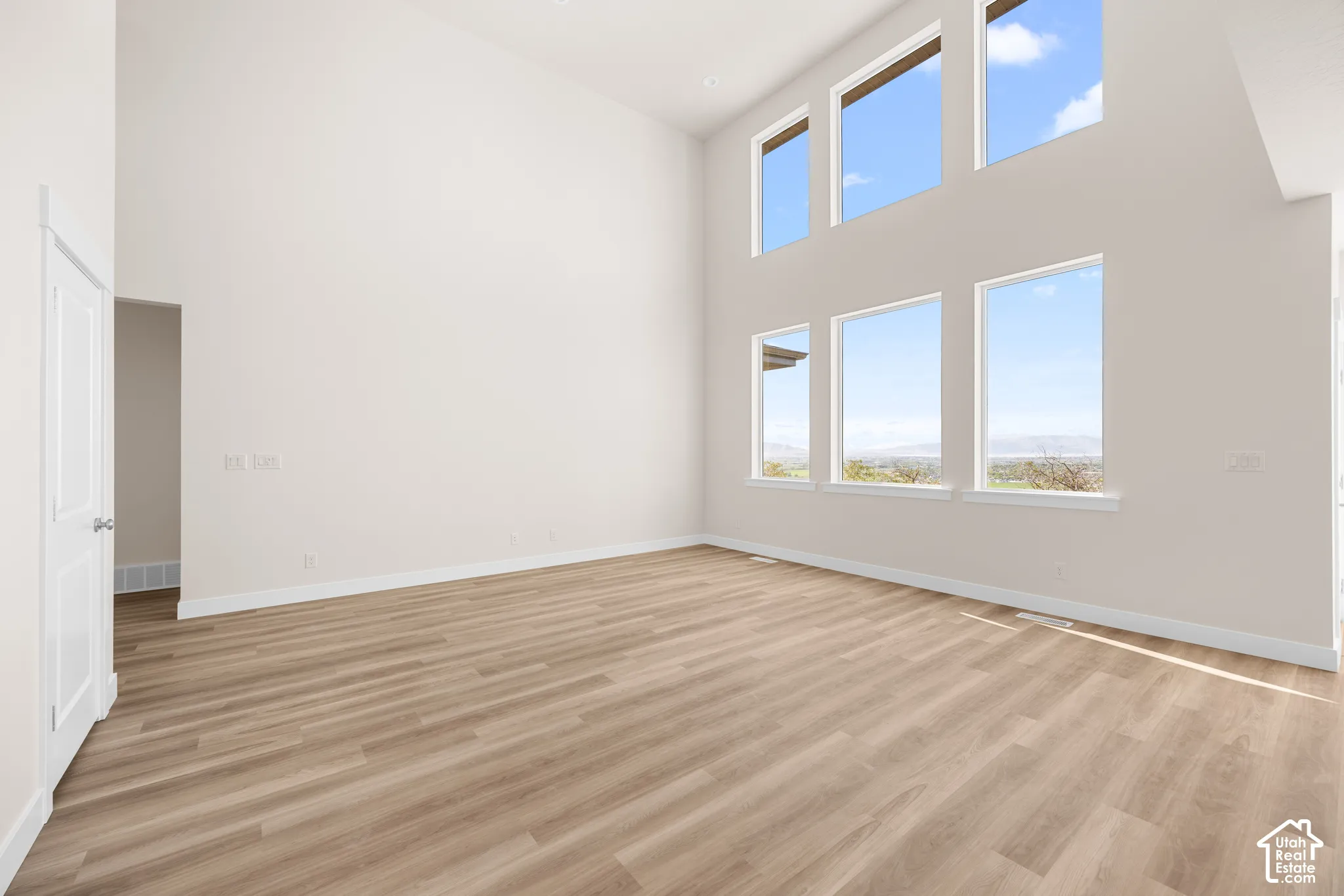 Vaulted ceiling, wood-finish flooring, white walls, and multiple large windows