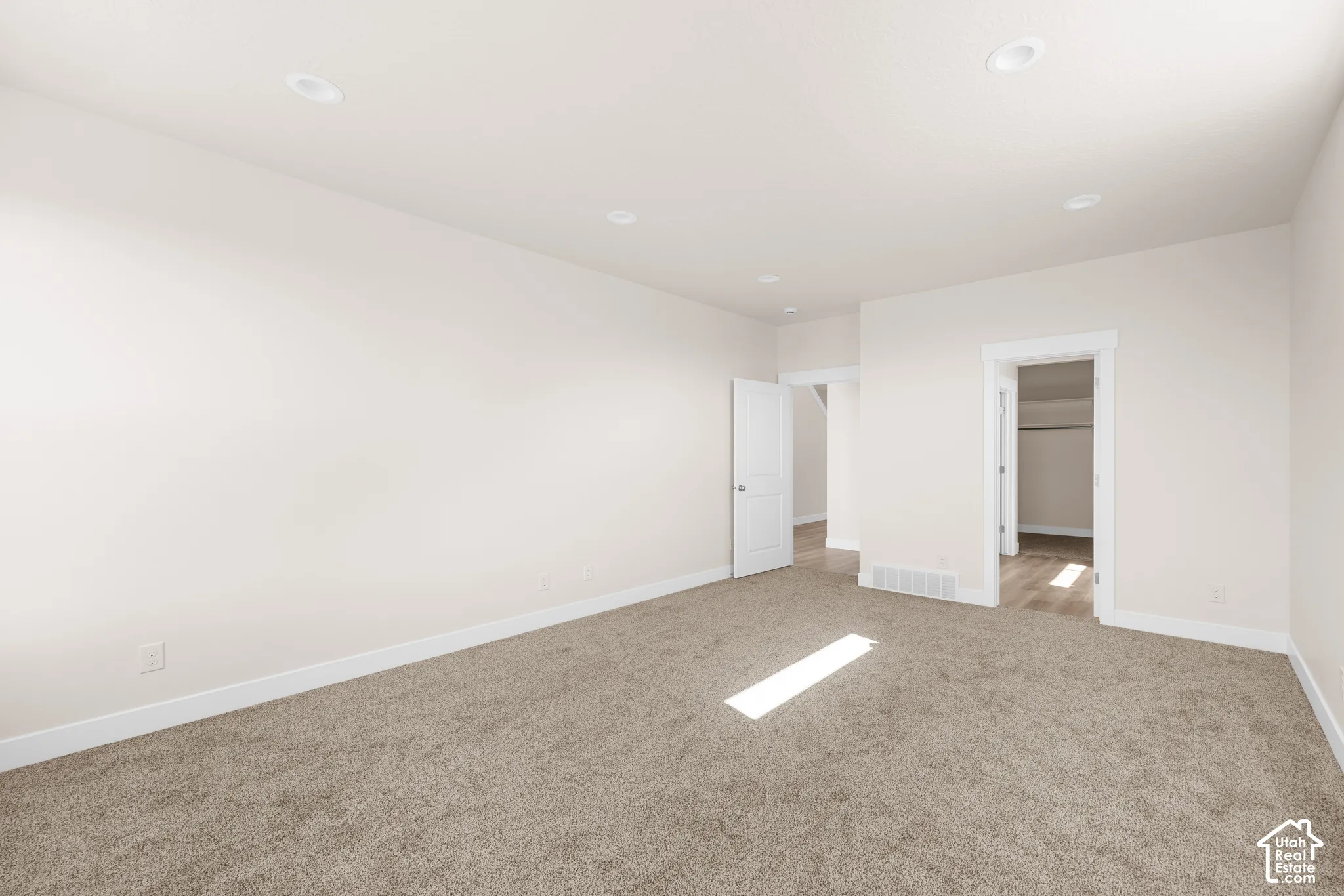 Plush carpet flooring, recessed ceiling lighting, crisp white walls, and white trim