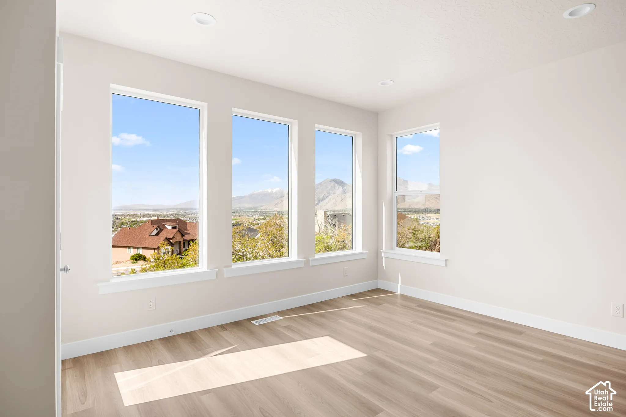 Light-filled interior featuring multiple windows, wood-finish flooring, recessed lighting, and white trim
