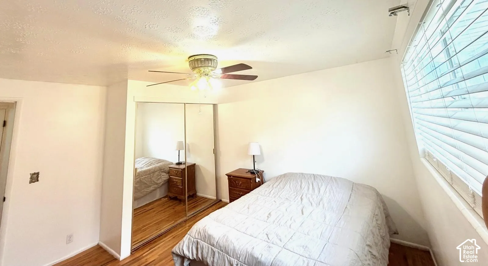 Vinyl flooring, mirrored closet doors, ceiling fan with integrated lighting, and window with horizontal blinds