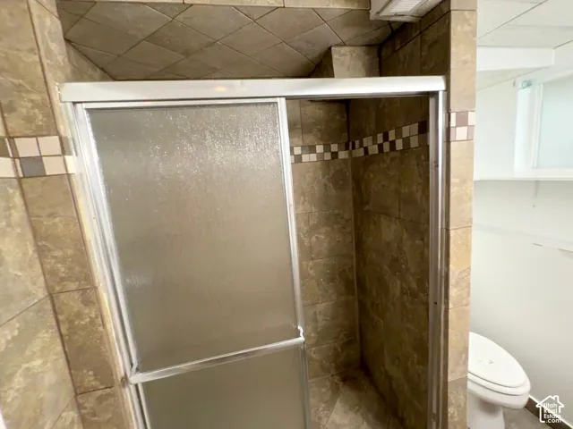 Tiled shower stall with sliding glass doors, accented by a decorative tile band