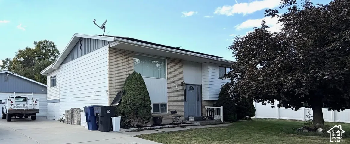 Brick and siding exterior with a pitched roof, front entry with a small porch, and a mature tree in the front yard