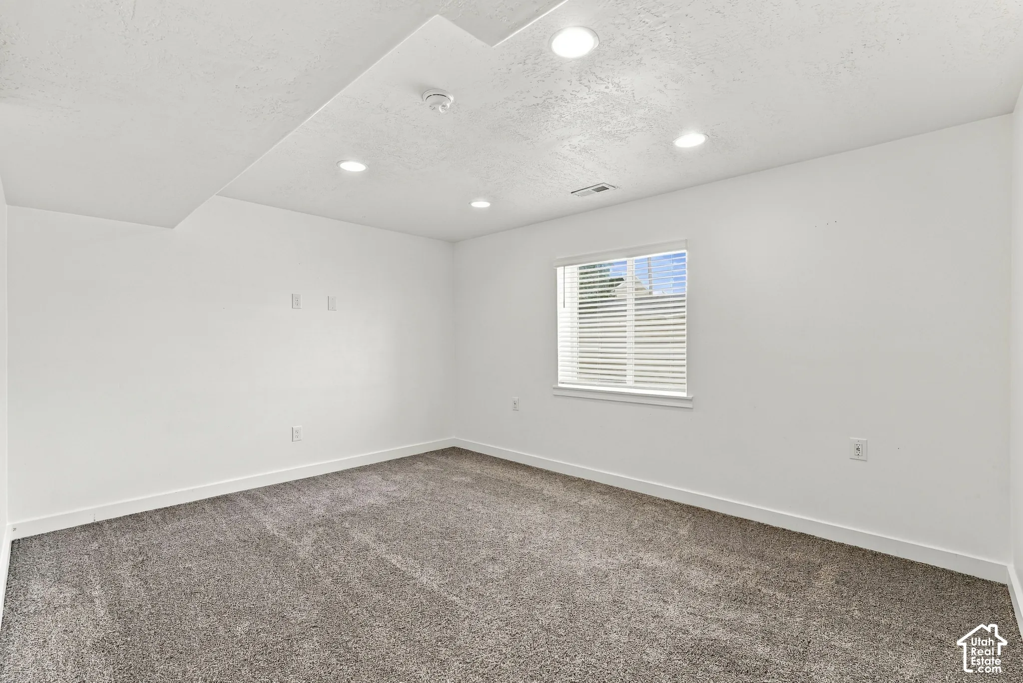 Recessed lighting illuminates fresh white walls and textured carpeting