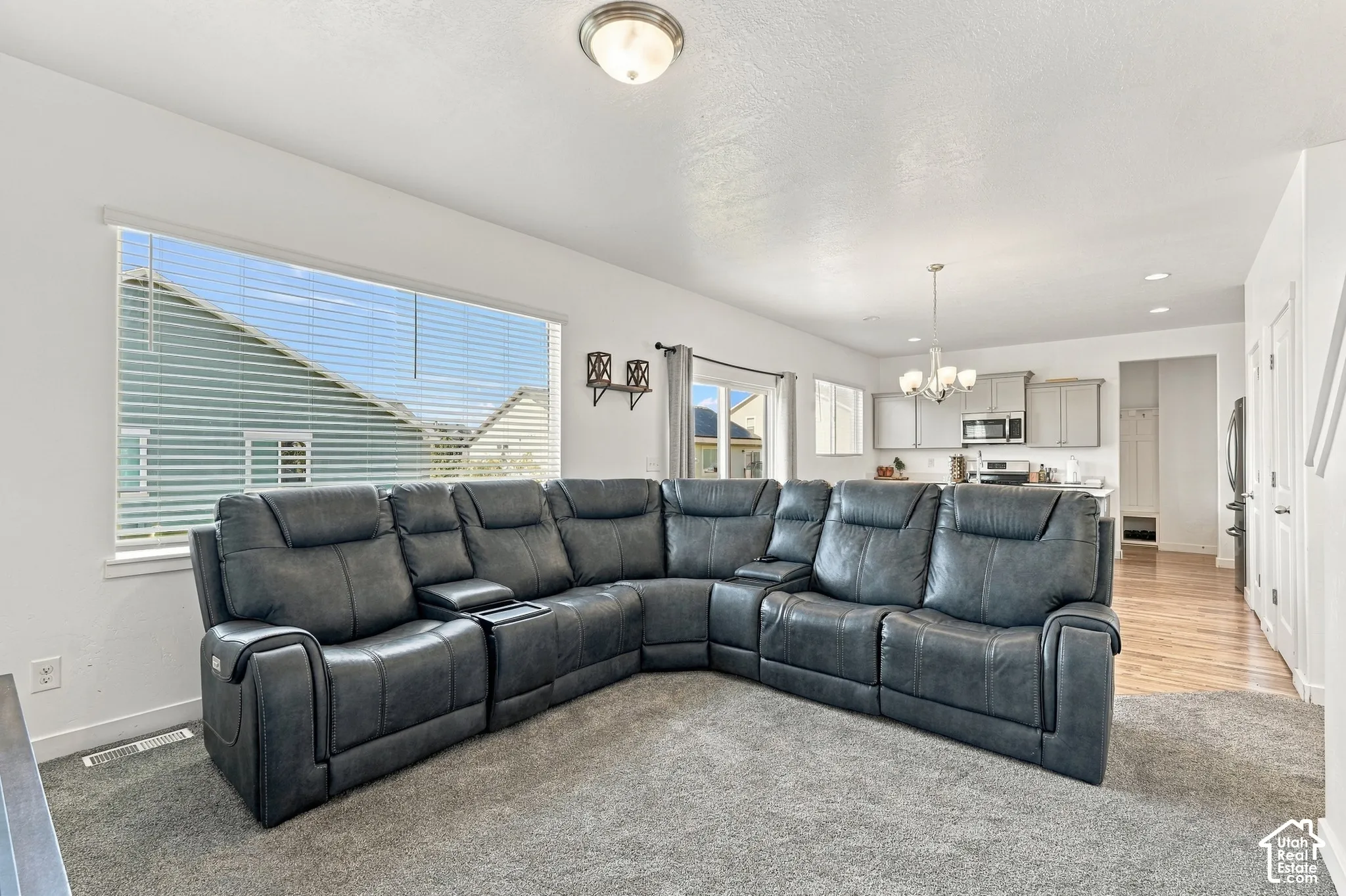 Open-concept living area with a large window, recessed lighting, and a chandelier