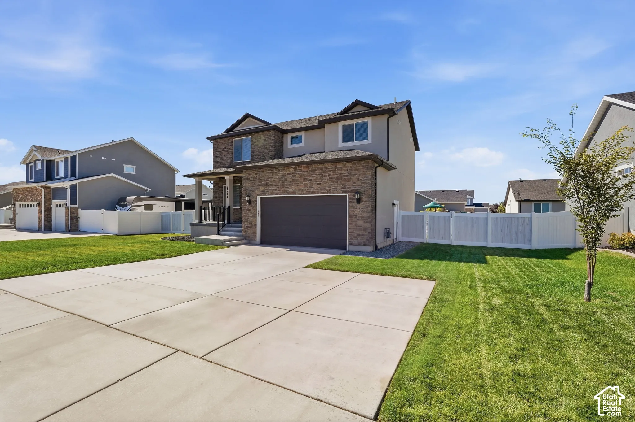 Two-story residence featuring a stone and stucco exterior, an attached two-car garage, and a RV pad