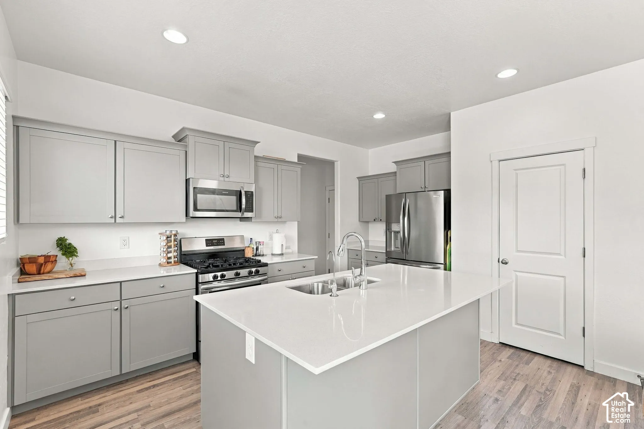 Kitchen featuring a center island, stainless steel appliances, light gray cabinetry, recessed lighting, and wood-finish flooring