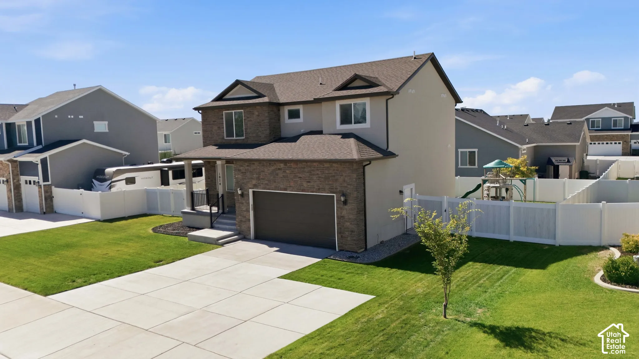 Two-story residence featuring brick and stucco exterior, an attached garage, and a concrete driveway and RV pad