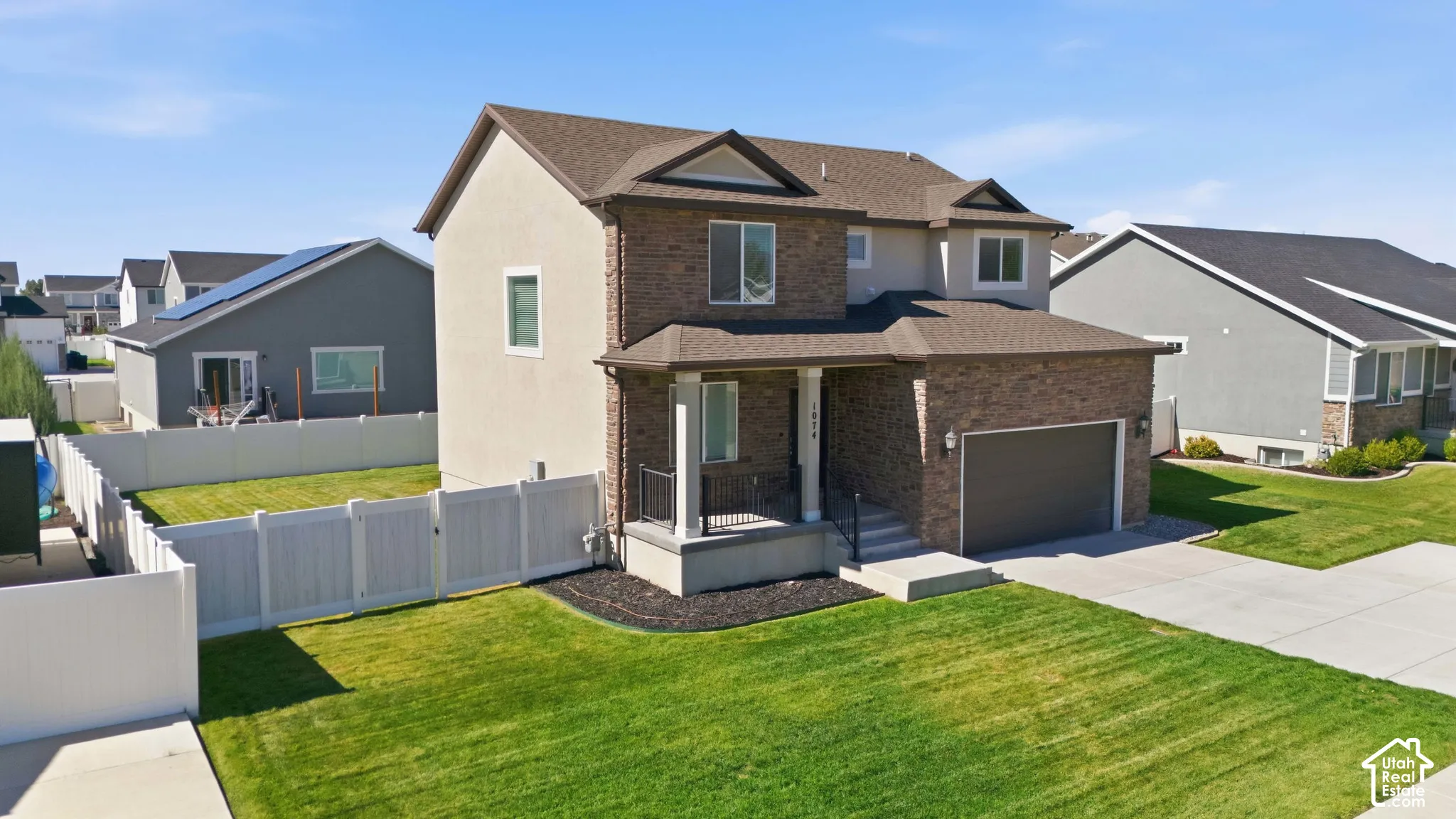 Two-story residence featuring brick and stucco siding, a two-car garage, and a covered front porch with railings
