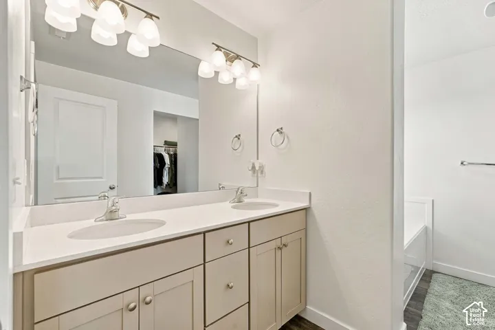 Primary bedroom bath with double vanity with undermount sinks, light-toned cabinetry, and a full-width mirror