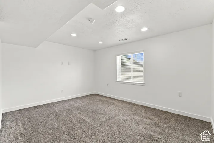 Recessed lighting illuminates fresh white walls and textured carpeting