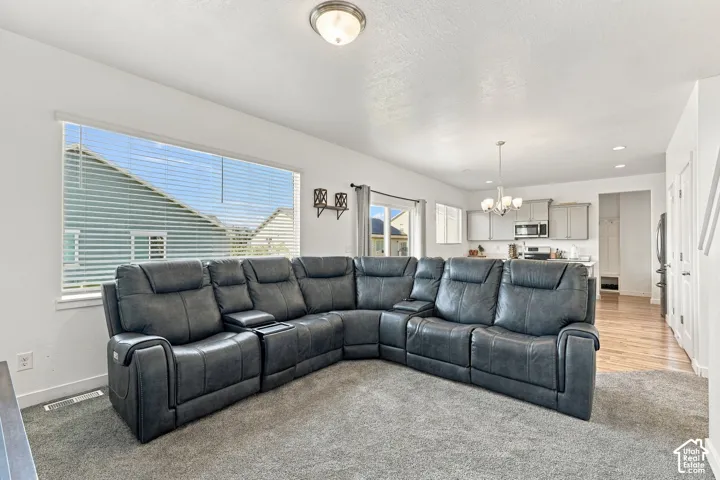 Open-concept living area with a large window, recessed lighting, and a chandelier