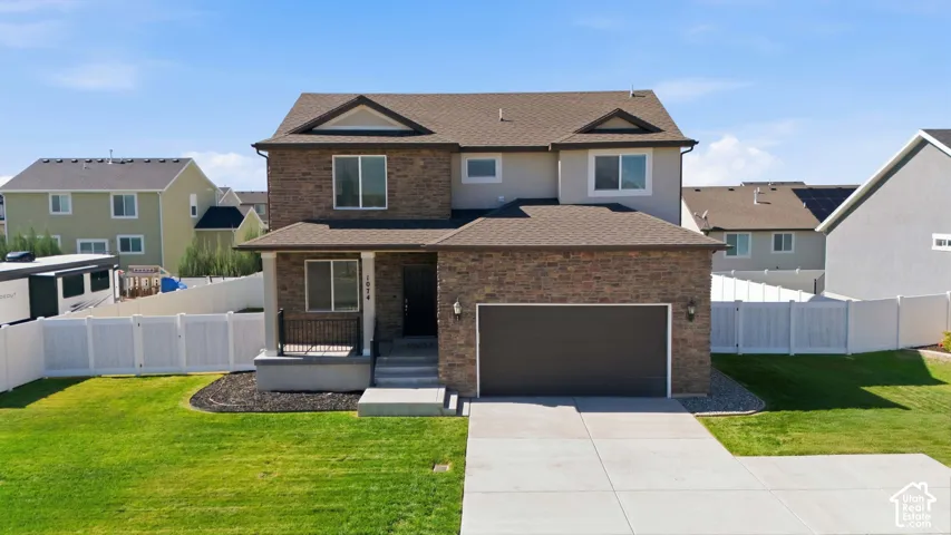 Brick and siding facade, covered front porch, two-car garage, concrete driveway, and manicured lawn