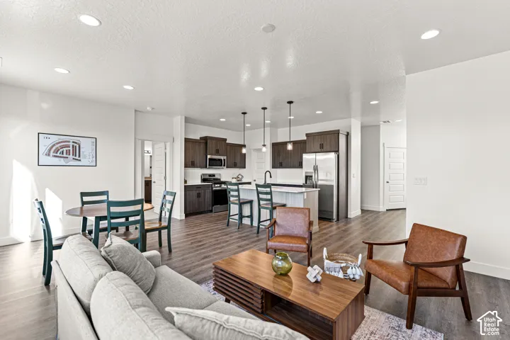 Open-concept living area with wood-finish flooring, recessed lighting, and a white color palette