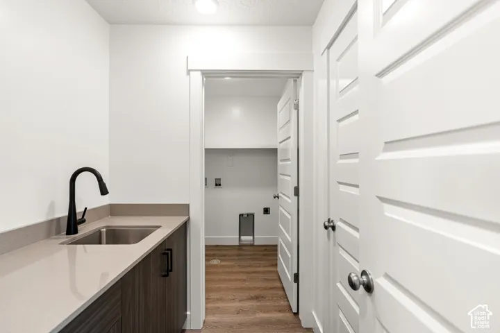 Sleek utility room featuring a stainless steel sink, matte black faucet, durable countertop, and wood-finish cabinetry