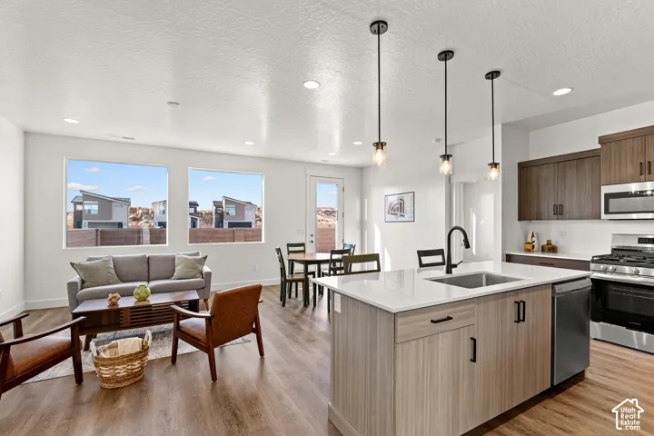 Open-concept living space featuring wood-finish flooring, recessed lighting, and large windows