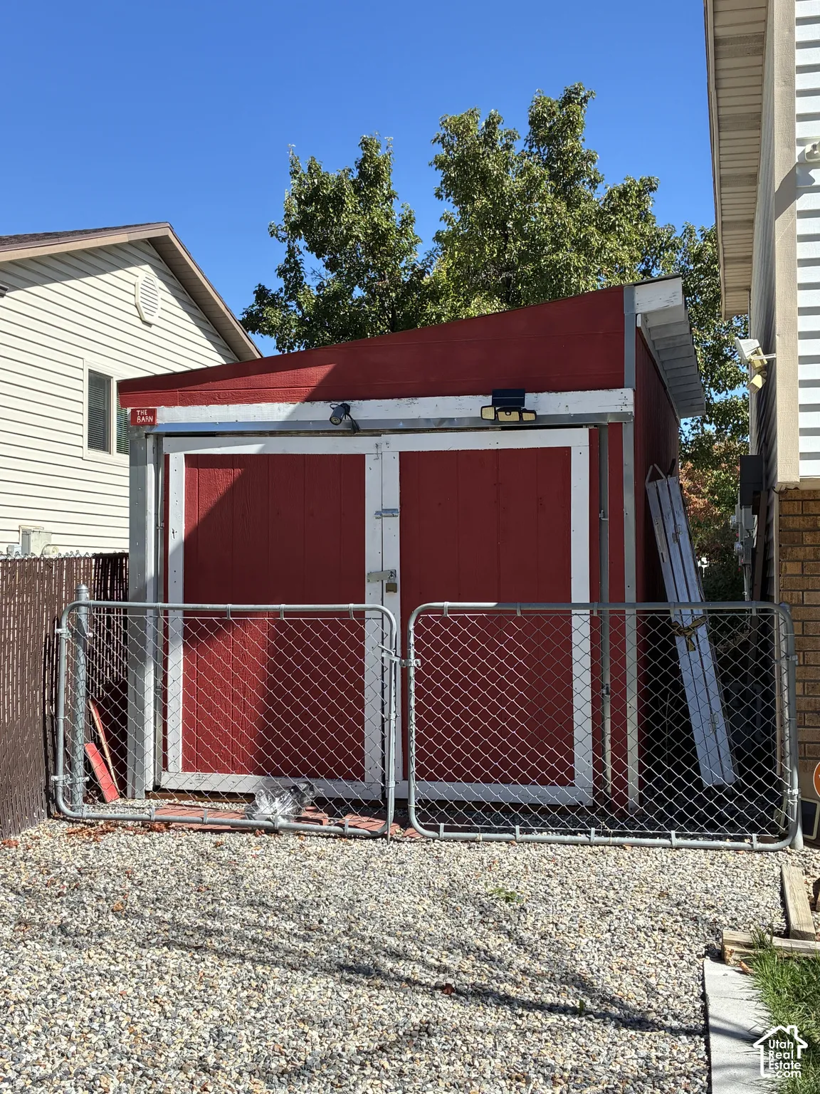 Red storage shed with double doors, pitched roofline, and gravel ground cover