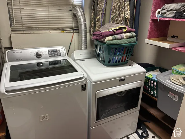 Laundry area featuring a top-load washing machine, front-load dryer, and wall-mounted shelving