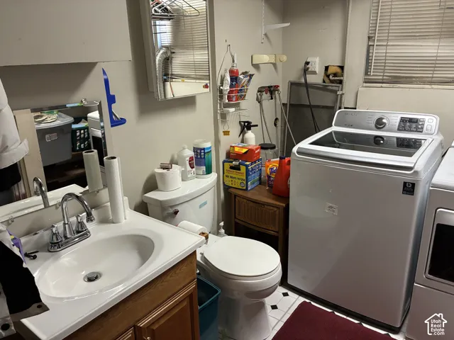 Bathroom with a white vanity sink, wood-finish cabinetry, and a toilet
