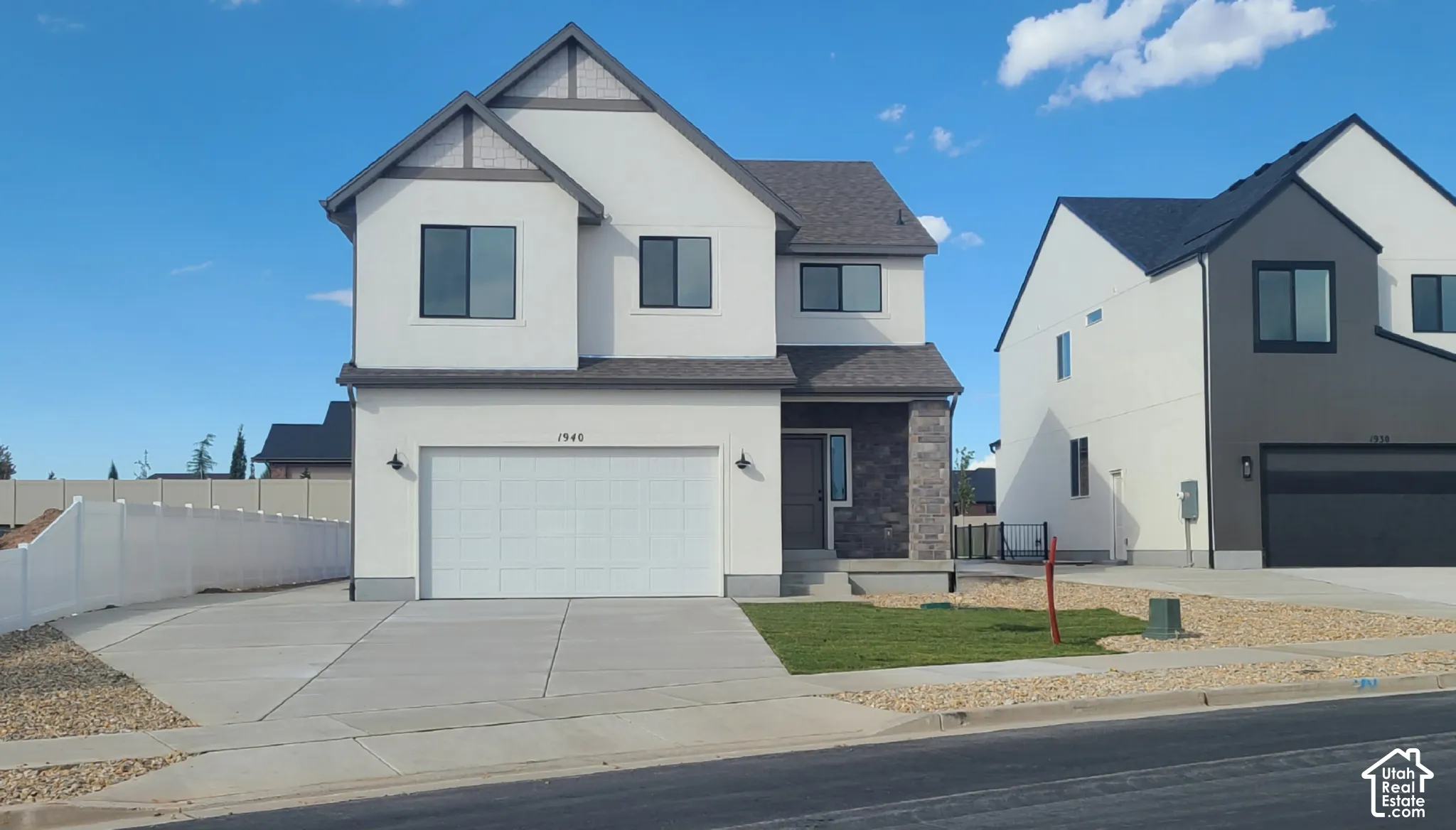 Two-story exterior featuring a stucco and stone facade, gabled rooflines, two-car garage, and concrete driveway