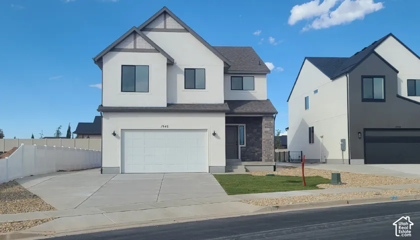Two-story exterior featuring a stucco and stone facade, gabled rooflines, two-car garage, and concrete driveway
