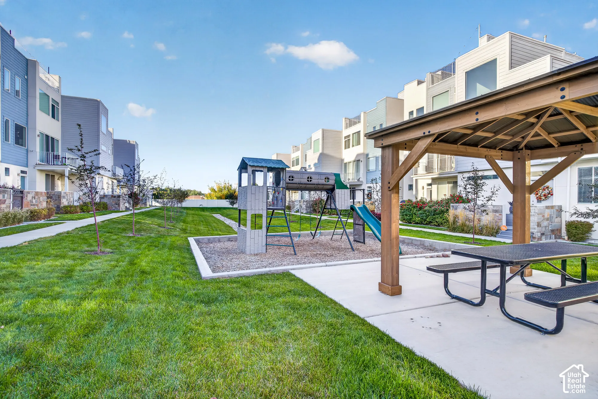Community green space featuring a wood gazebo with a picnic table, a playground with a slide, and a manicured lawn
