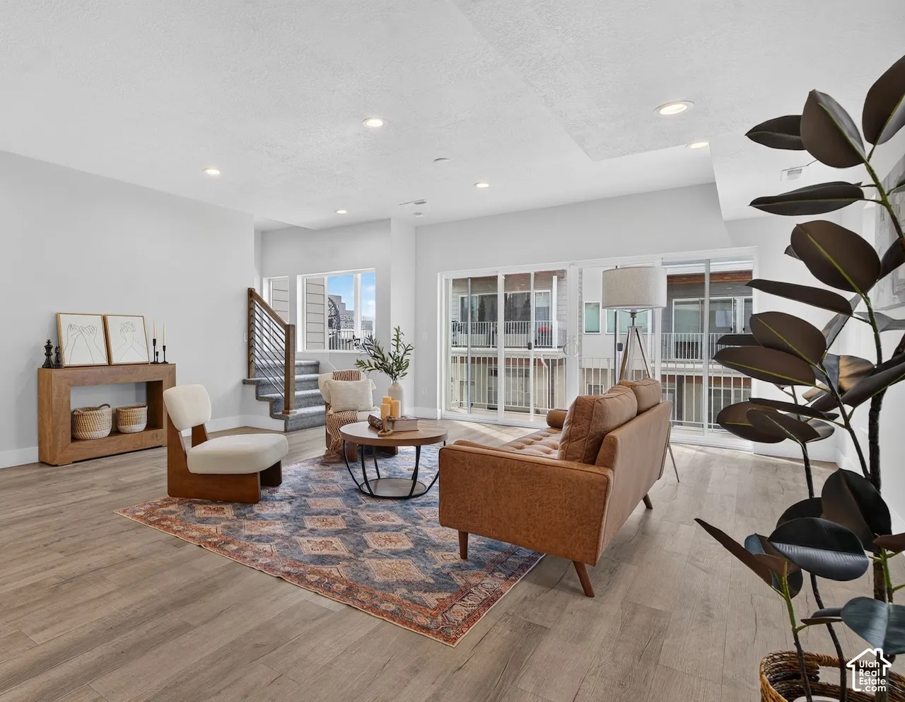 Recessed ceiling lighting, wood-finish flooring, staircase with metal railing, sliding glass doors, and a window with blinds