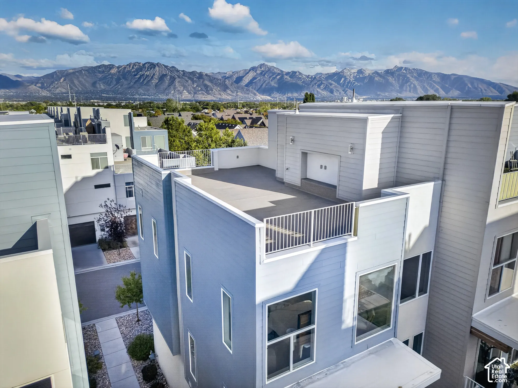 Multi-level modern exterior with a rooftop patio, contemporary siding, large windows, and a mountain backdrop