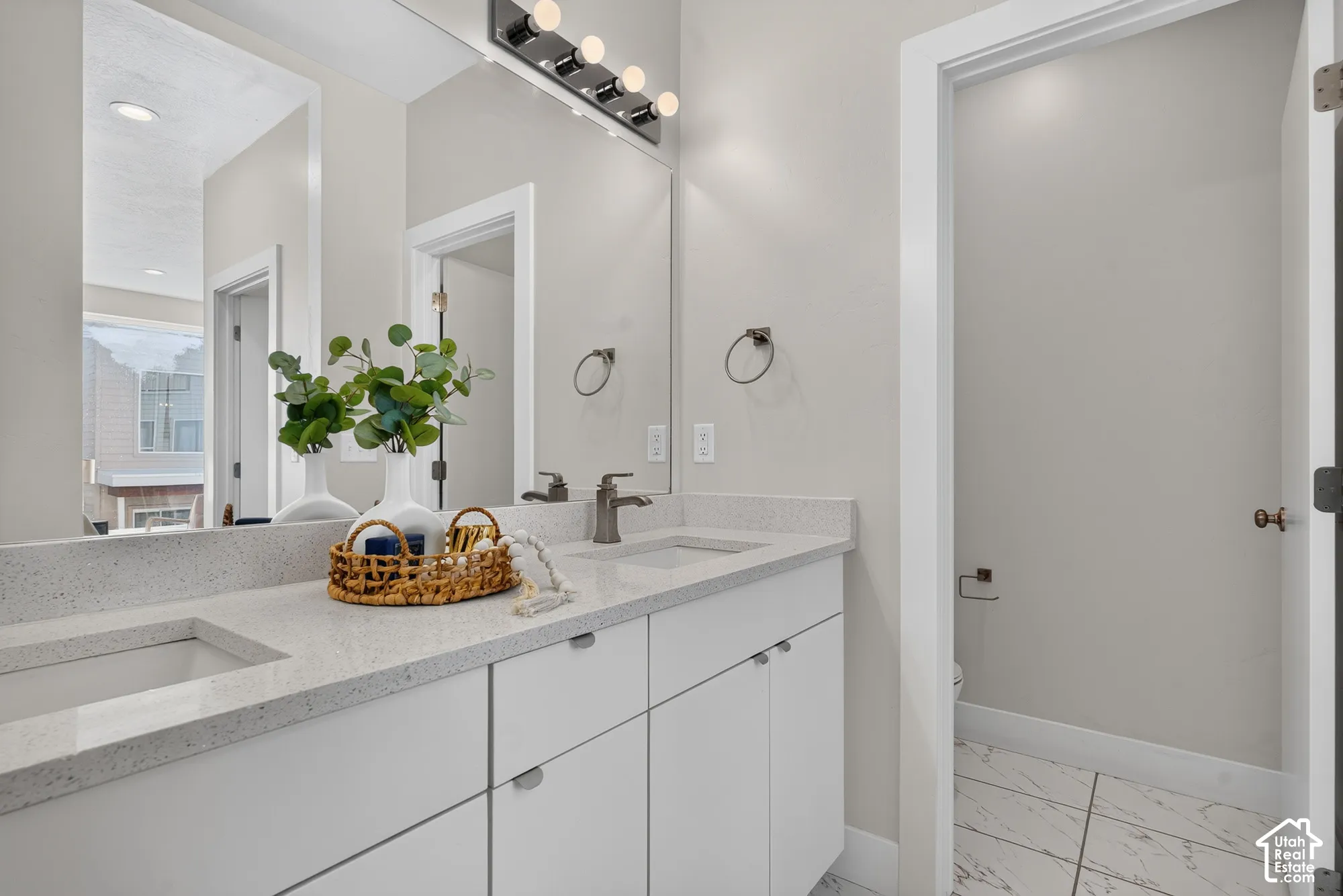 Dual undermount sinks with light-toned countertops and white cabinetry
